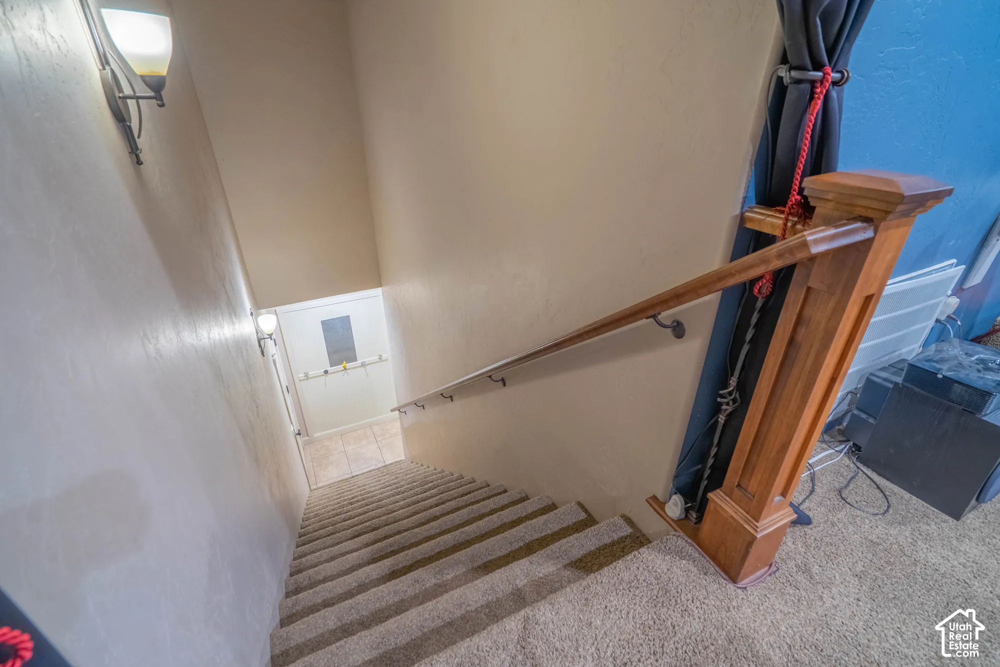 Carpeted staircase with a wood-finish newel post and handrail