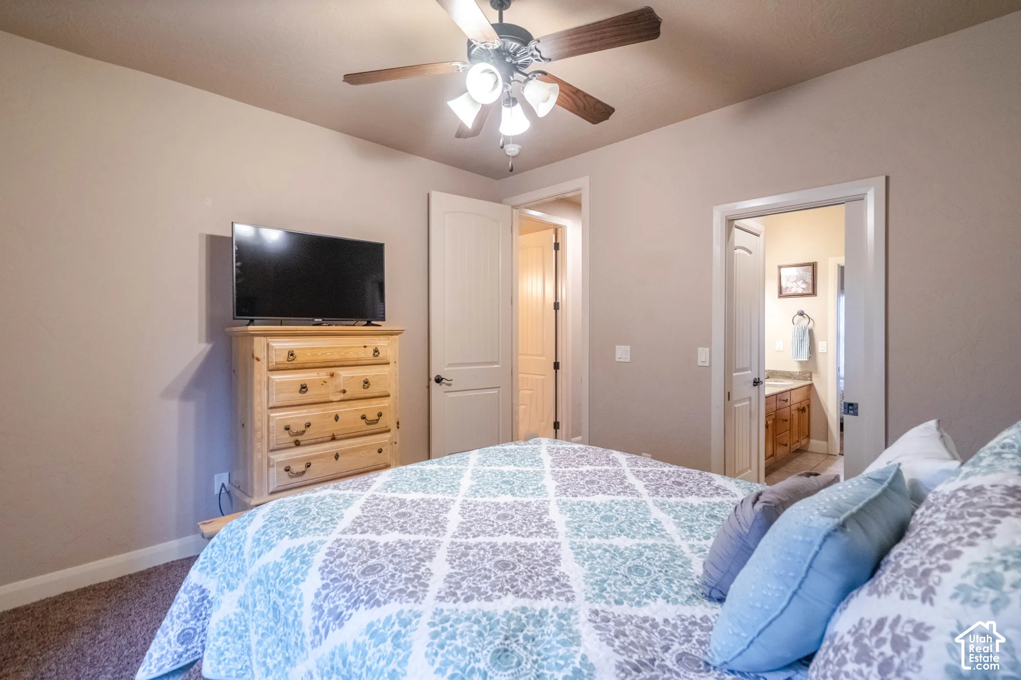Textured carpeting, neutral wall tones, and a ceiling fan with integrated lighting