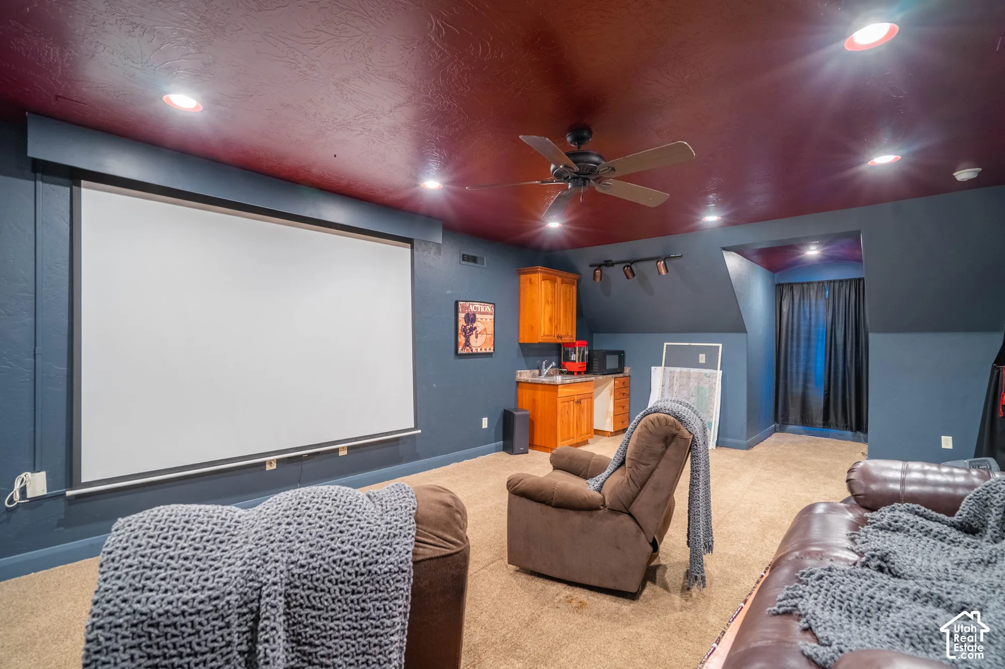 Integrated projector screen, recessed ceiling lighting, ceiling fan, built-in cabinetry with sink, and track lighting