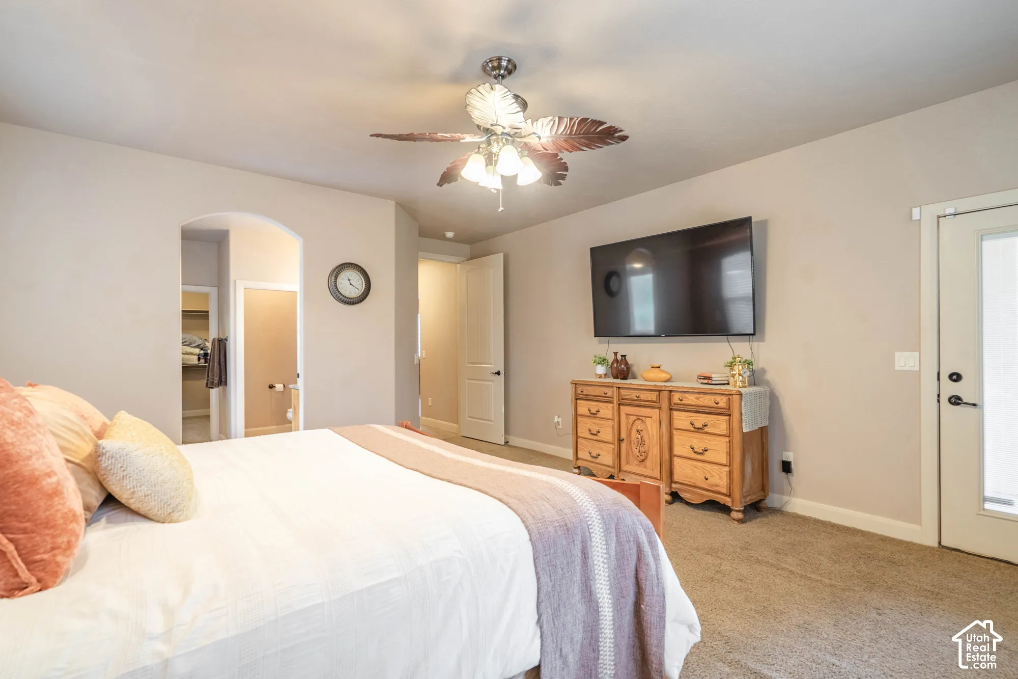 Arched doorway, ceiling fan with integrated lighting, wall-mounted television, and carpeted flooring