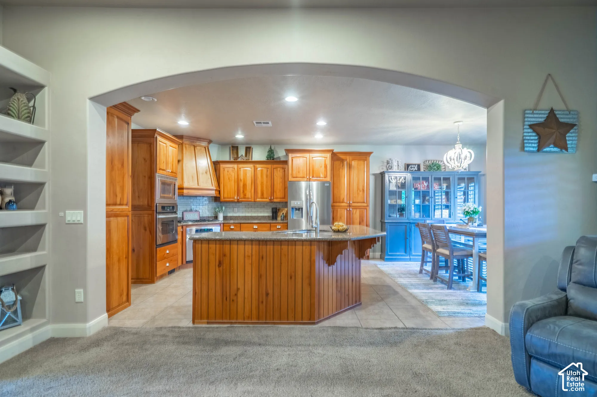 Kitchen featuring wood cabinetry, stainless steel appliances, a center island with bar seating, and tile flooring
