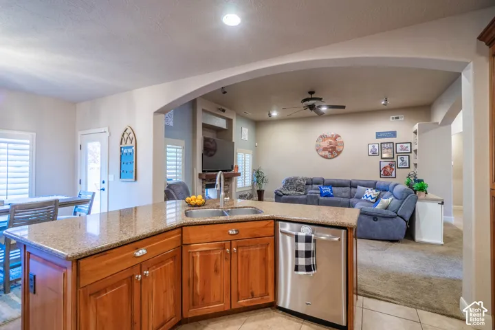 Kitchen island with granite-style countertop, wood cabinetry, and stainless steel dishwasher