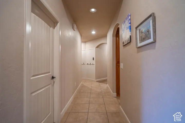 Hallway featuring tile flooring, recessed lighting, arched doorways, and textured wall finishes