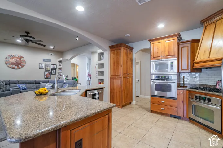 Kitchen with light wood cabinetry, granite countertops, tile flooring, and stainless steel appliances
