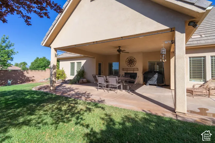 Expansive covered patio with a built-in fireplace, ceiling fan, and tile roof