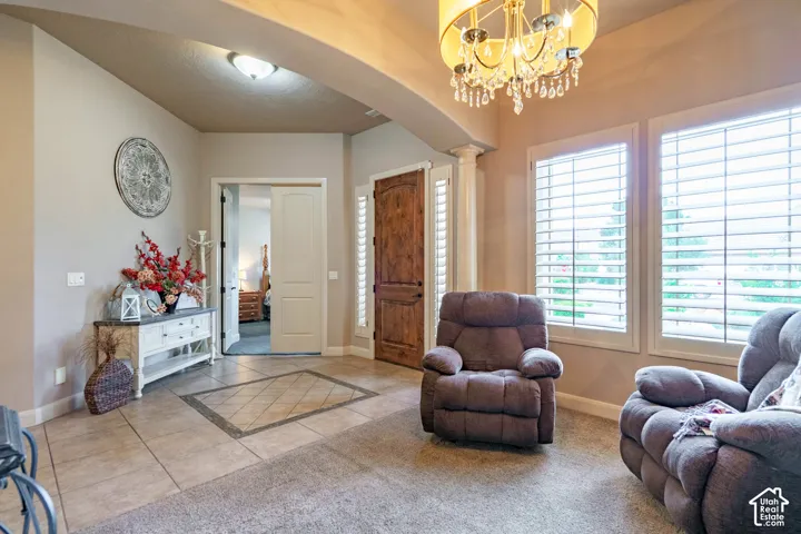 Arched entryway with a decorative chandelier, custom wooden entry door, and plantation shutters