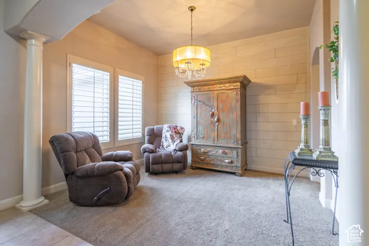 Arched entryway with a decorative column, shiplap accent wall, chandelier light fixture, and plantation shutters