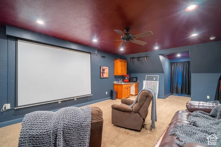 Integrated projector screen, recessed ceiling lighting, ceiling fan, built-in cabinetry with sink, and track lighting