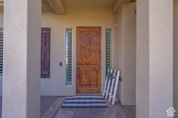 Arched wooden entry door with sidelight windows, sheltered by a stucco-finished entryway