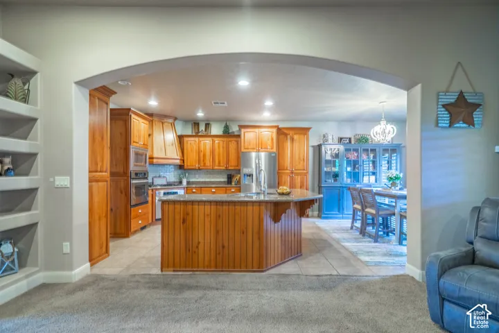 Kitchen featuring wood cabinetry, stainless steel appliances, a center island with bar seating, and tile flooring