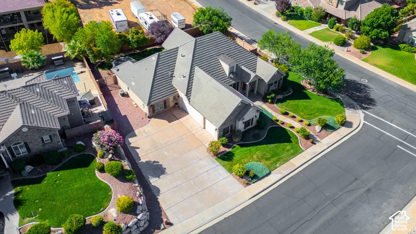 Spacious corner property with a multi-gabled roof, extensive concrete driveway, and established front landscaping