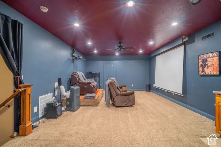 Built-in projection screen with dark-toned walls, recessed lighting, and a ceiling fan