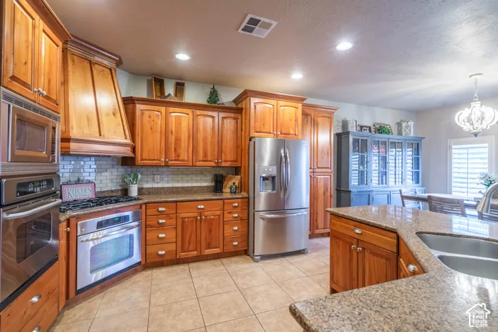 Wood-finish cabinetry, stainless steel appliances, tile flooring, stone countertops, and recessed lighting