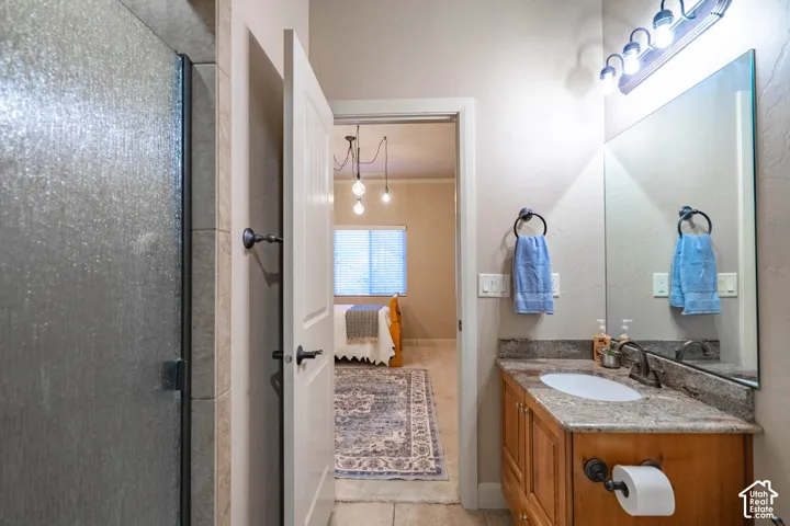 Bathroom featuring a single vanity with wood cabinetry, a built-in sink, and a stone countertop