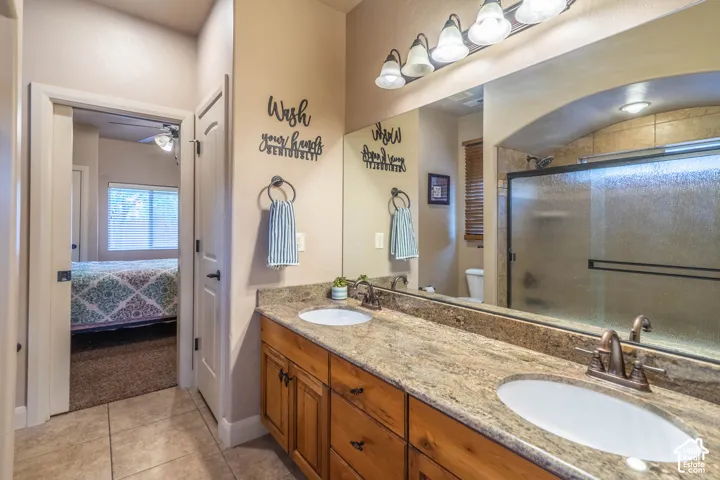 Dual vanity with integrated sinks, wood-finish cabinetry, and a stone-finish countertop