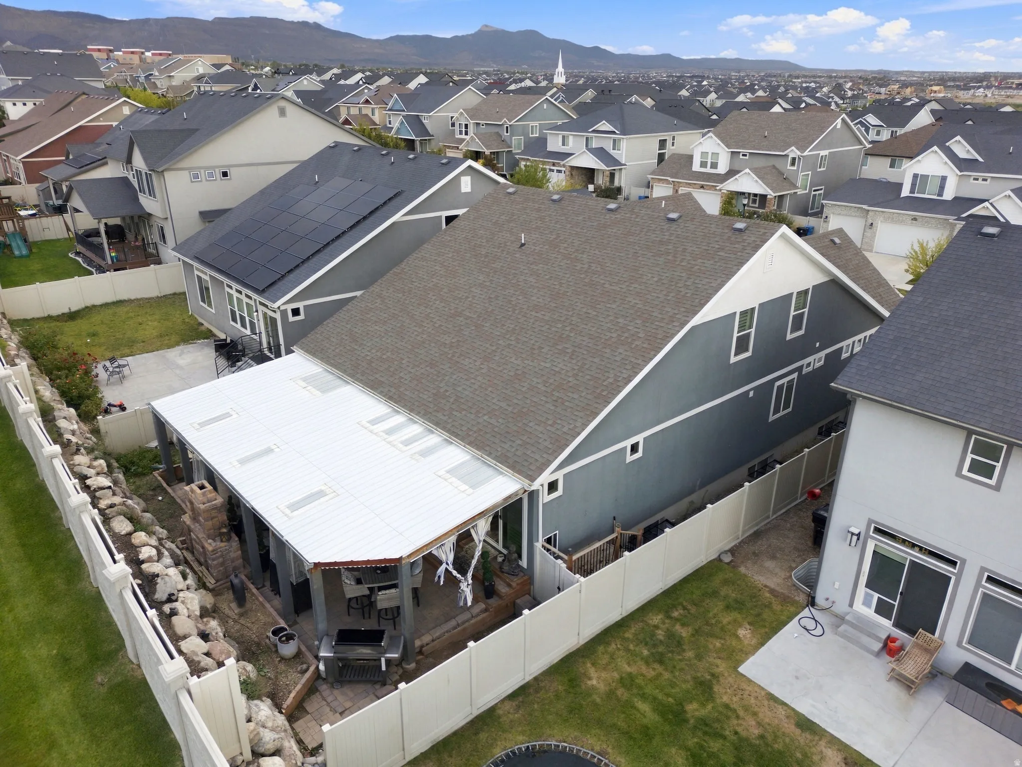 Rear exterior with covered patio, solar panel array, and mountain backdrop