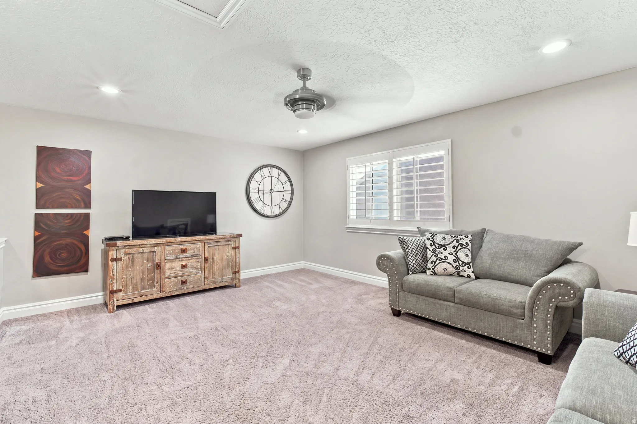 Recessed lighting, ceiling fan, window with plantation shutters, and light-colored carpeting