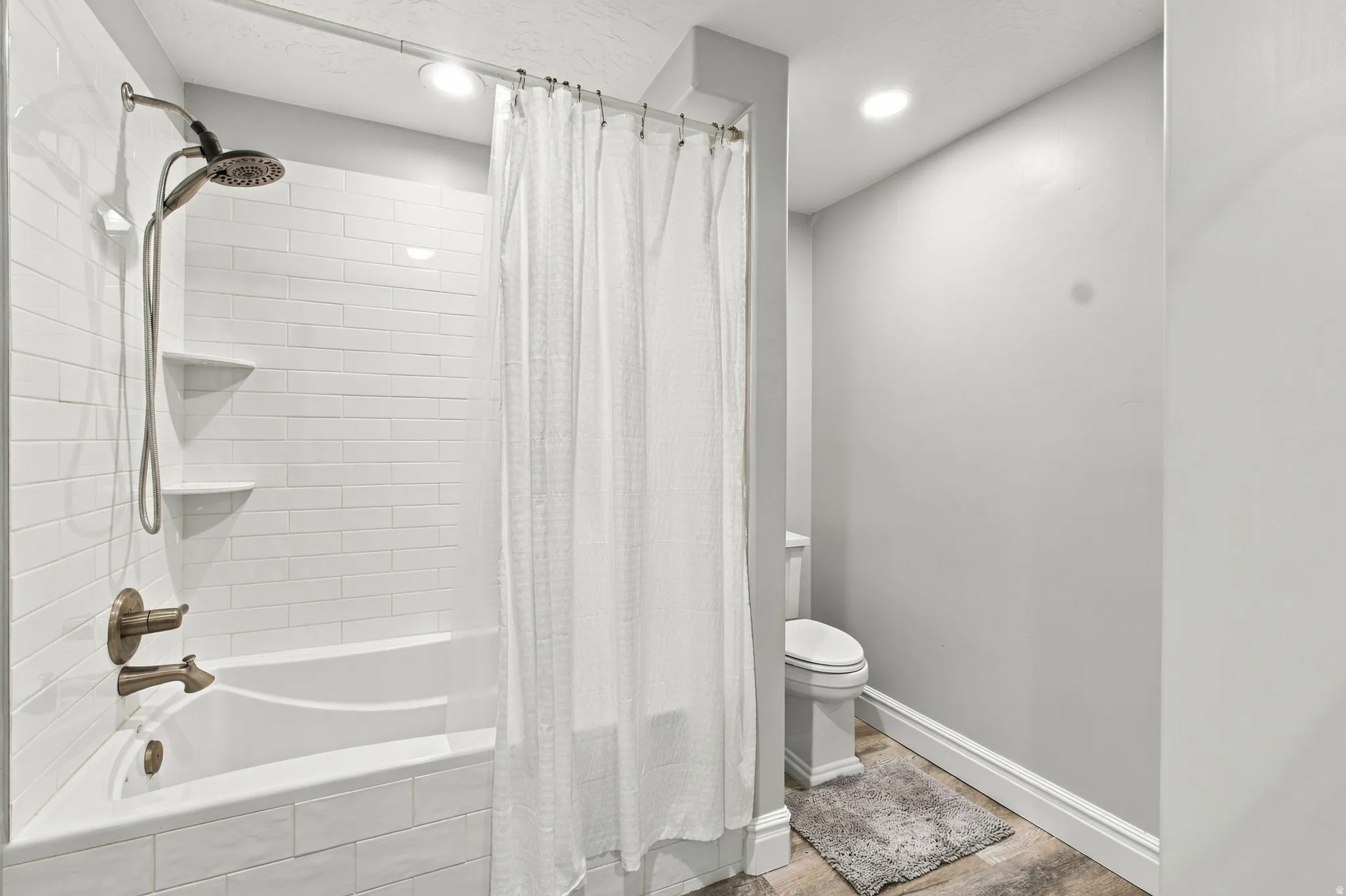 White subway tile surround, built-in shower shelving, and bronze-finish plumbing fixtures