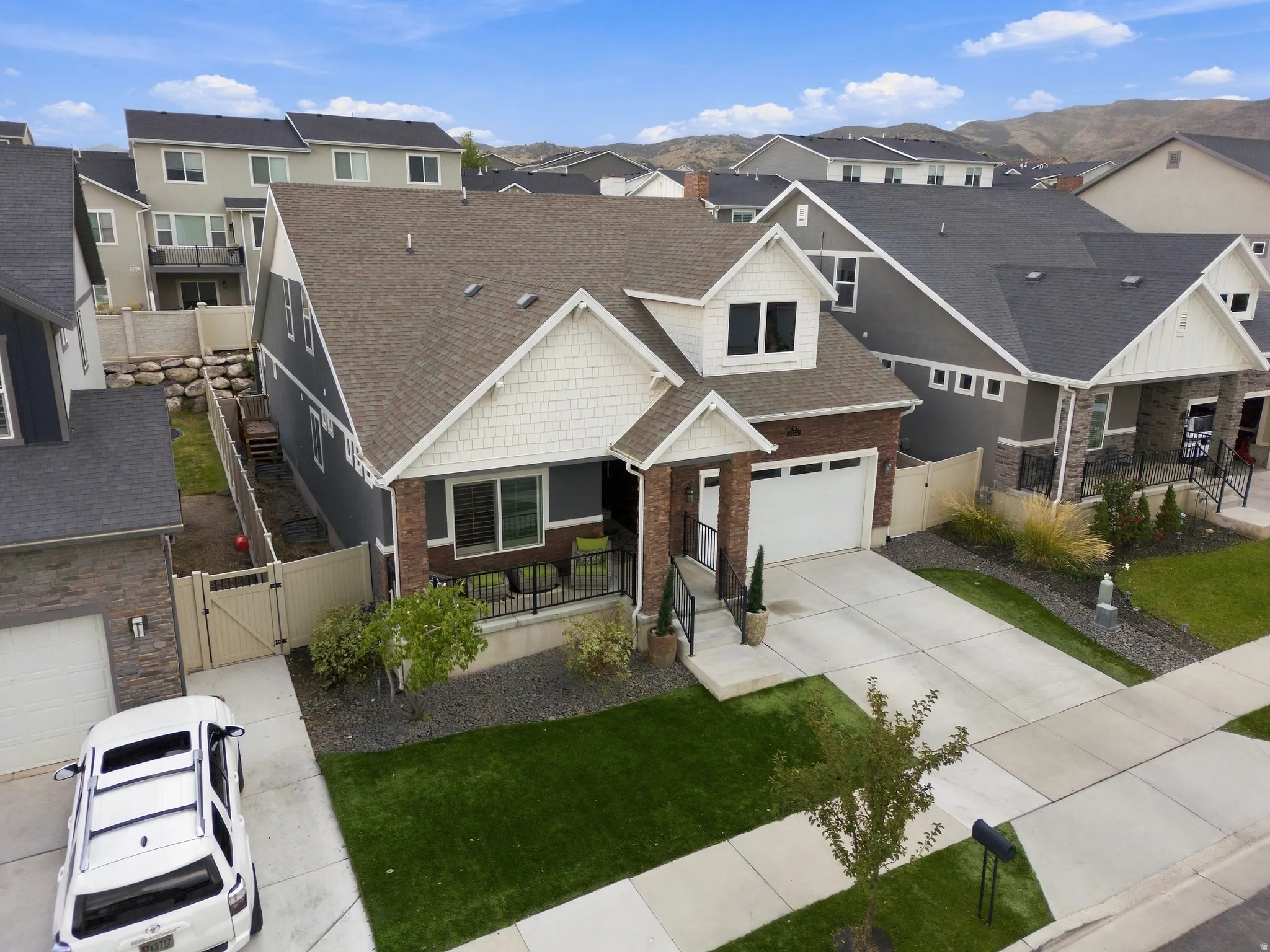 Two-story residence featuring a brick and siding exterior, an attached two-car garage, and a covered front porch