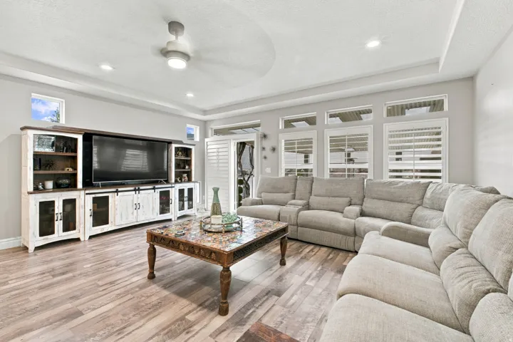Wood-finish flooring with a multi-pane window wall, transom windows, and white plantation shutters