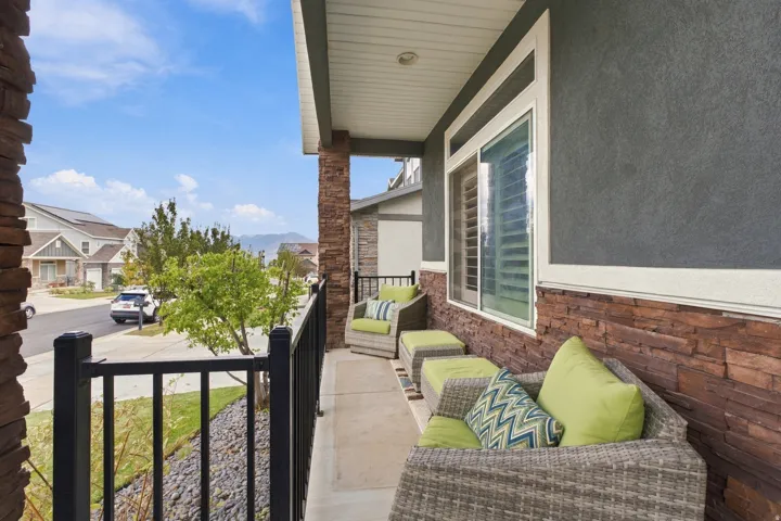 Exterior balcony featuring stacked stone accents, stucco siding, and a white framed window with interior shutters