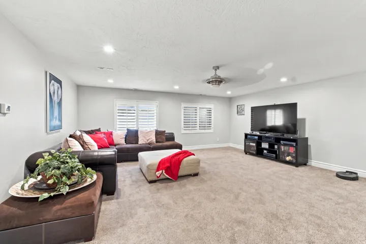 Recessed lighting, ceiling fan, white window shutters, light gray wall paint, and carpeting
