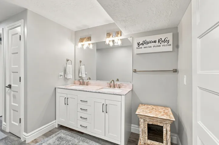Double vanity with white cabinetry, dual sinks, and light-toned countertop
