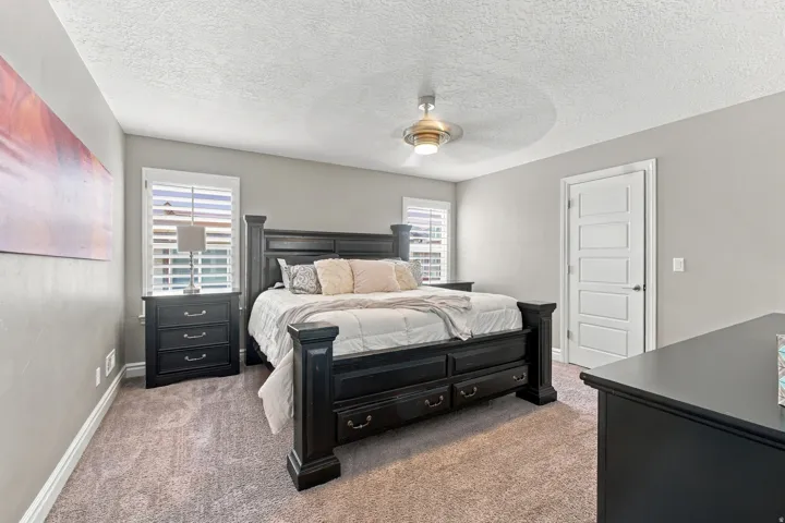 Recessed windows with plantation shutters, ceiling fan with integrated lighting, paneled interior door, and neutral wall paint