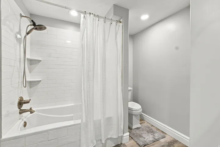 White subway tile surround, built-in shower shelving, and bronze-finish plumbing fixtures