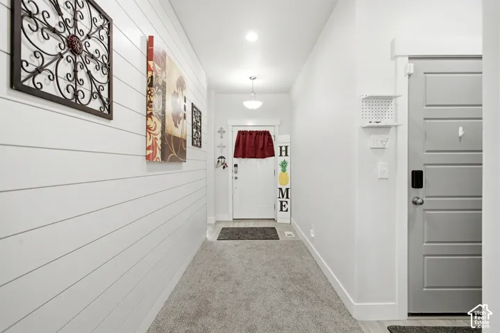 Carpeted hallway featuring a shiplap accent wall, white trim
