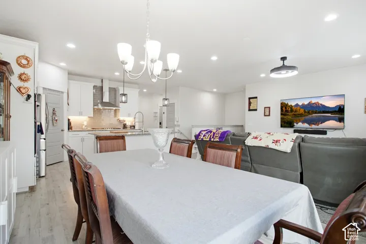 Open-concept interior featuring light wood-finish flooring, recessed lighting, and a modern chandelier