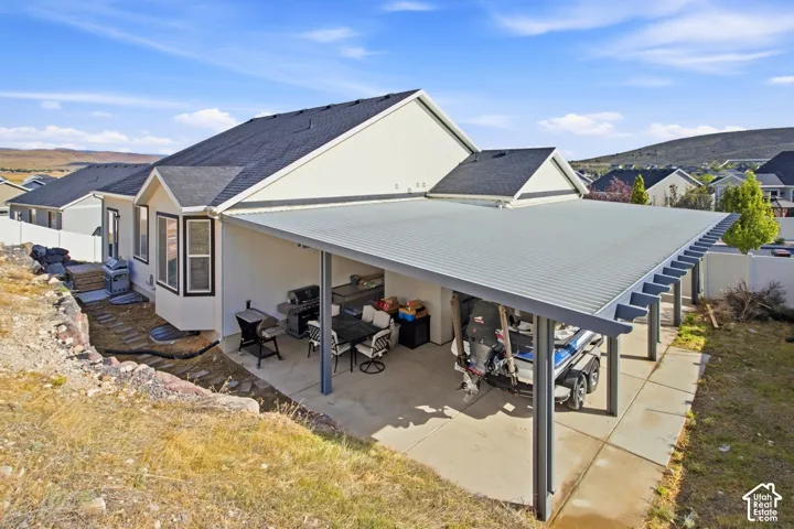 Covered patio with concrete flooring, bay window, dark shingle roof, and exterior wall siding