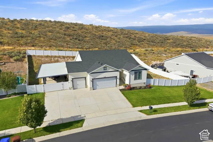 Single-story residence featuring a two-car garage, an additional carport, and a white vinyl privacy fence enclosing the yard