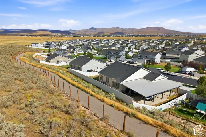 Residential neighborhood with a paved walking path bordering a natural landscape and distant mountains