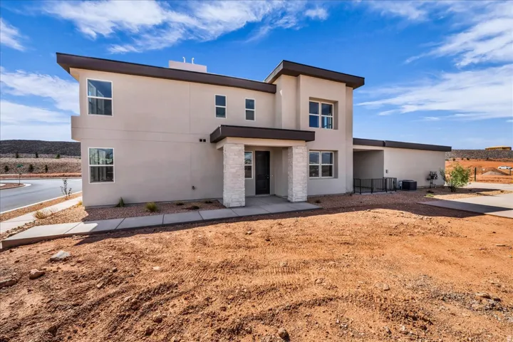 Stucco exterior, stone facade accents, multiple windows, covered entry, and attached garage space