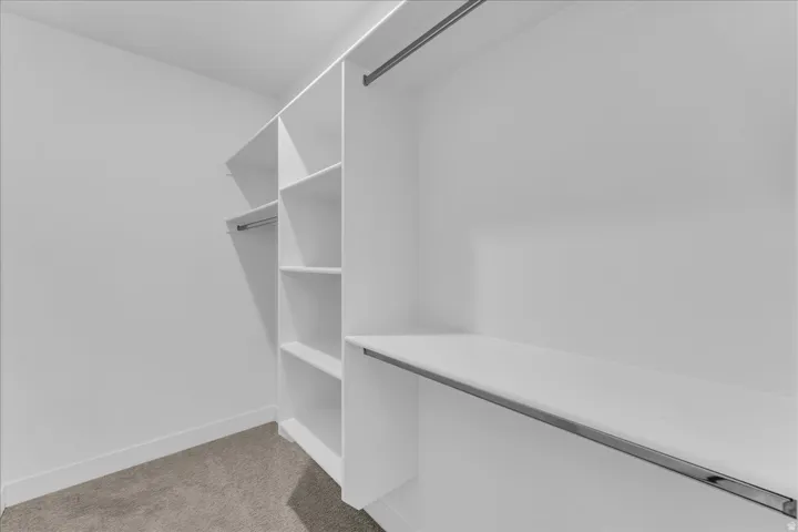 Walk-in closet with built-in shelving, two hanging rods, and light-colored carpeting