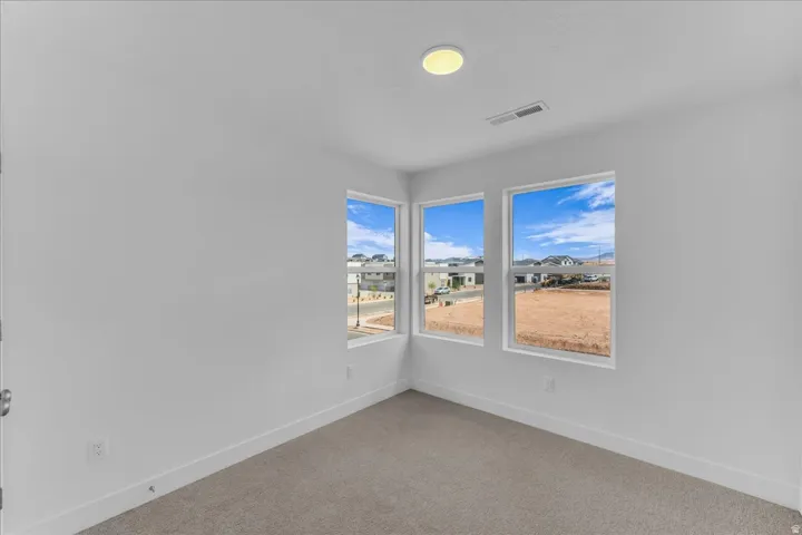 Three large windows, neutral wall finishes, flush mount ceiling lighting, and carpet flooring