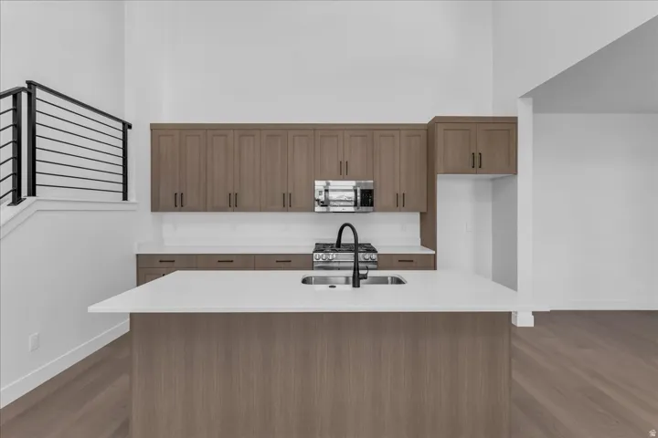 Kitchen featuring wood-finish cabinetry, white countertops, built-in microwave, gas range, and a dual-basin sink with a matte black faucet