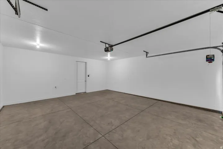 Spacious garage featuring a concrete floor, bright overhead lighting, and an automatic garage door opener