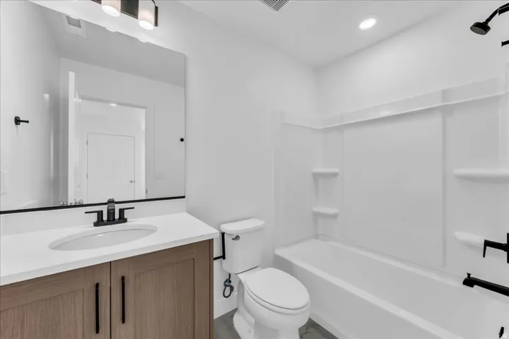 Wood-finish vanity with a white countertop and oval undermount sink, accented by a black faucet