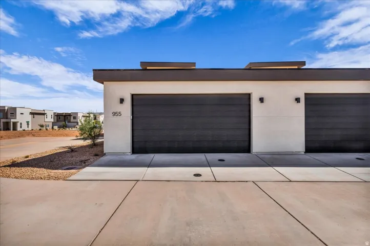 Modern exterior with stucco finish, two dark-toned garage doors, and contemporary exterior lighting fixtures