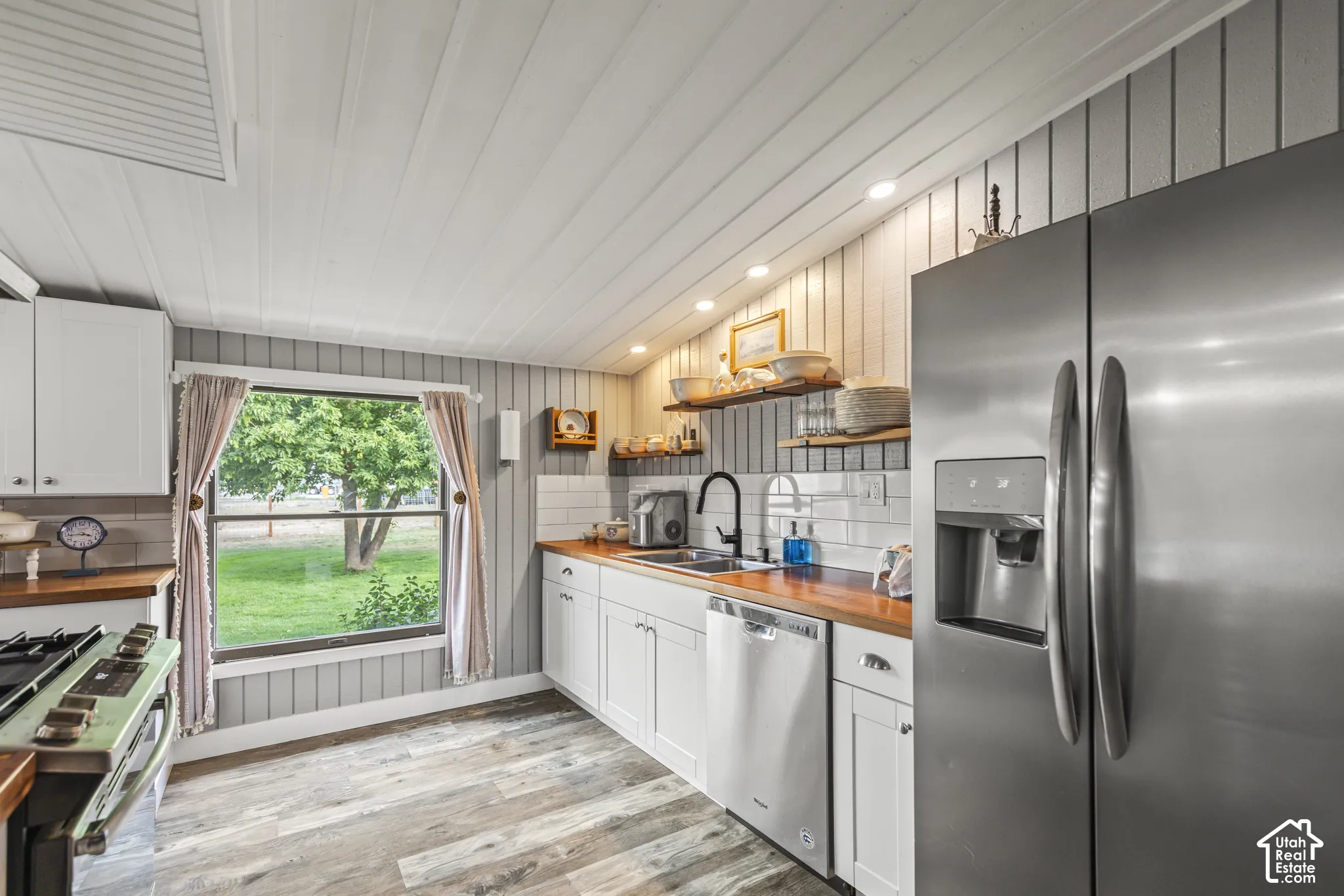 Kitchen featuring wood-finish flooring, white cabinetry, wood countertops, and stainless steel appliances