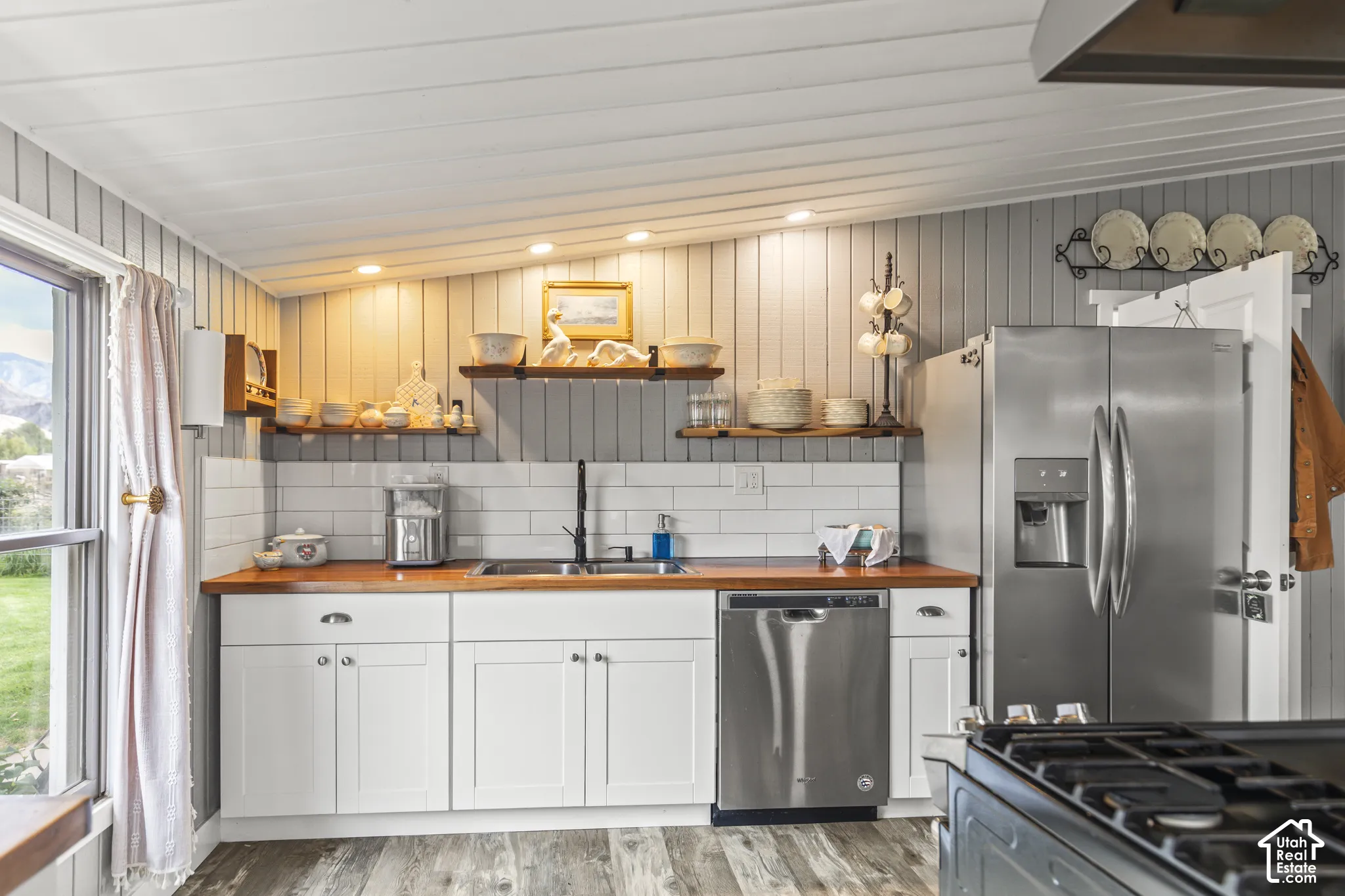 White shaker-style cabinetry with wood countertops, subway tile backsplash, and stainless steel appliances