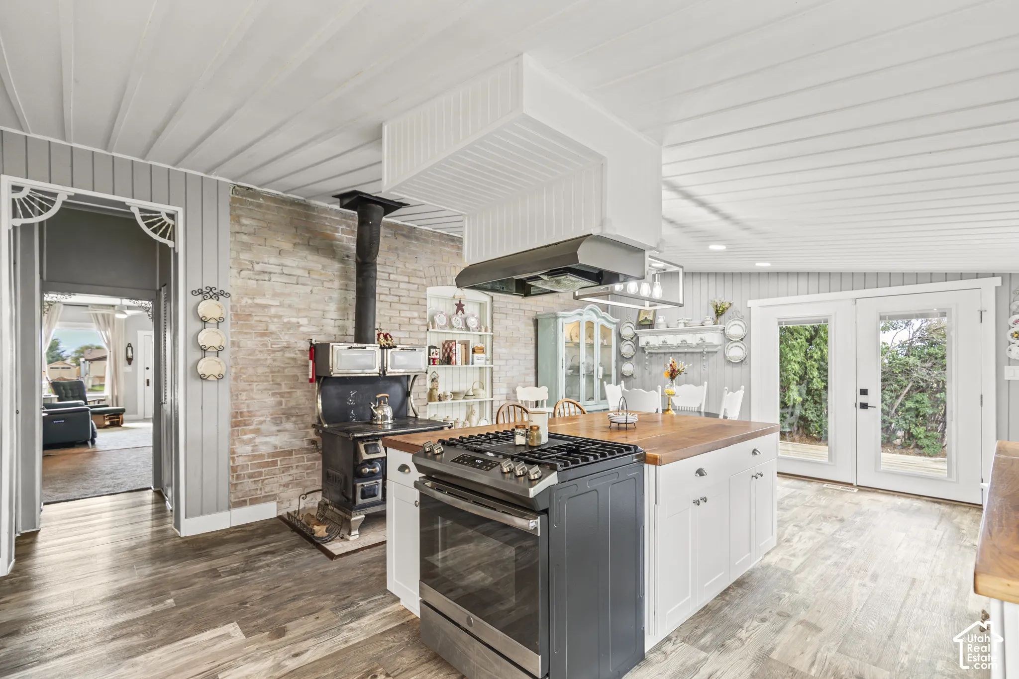 Kitchen featuring a central island with wood-finish countertop, white cabinetry, and a built-in range