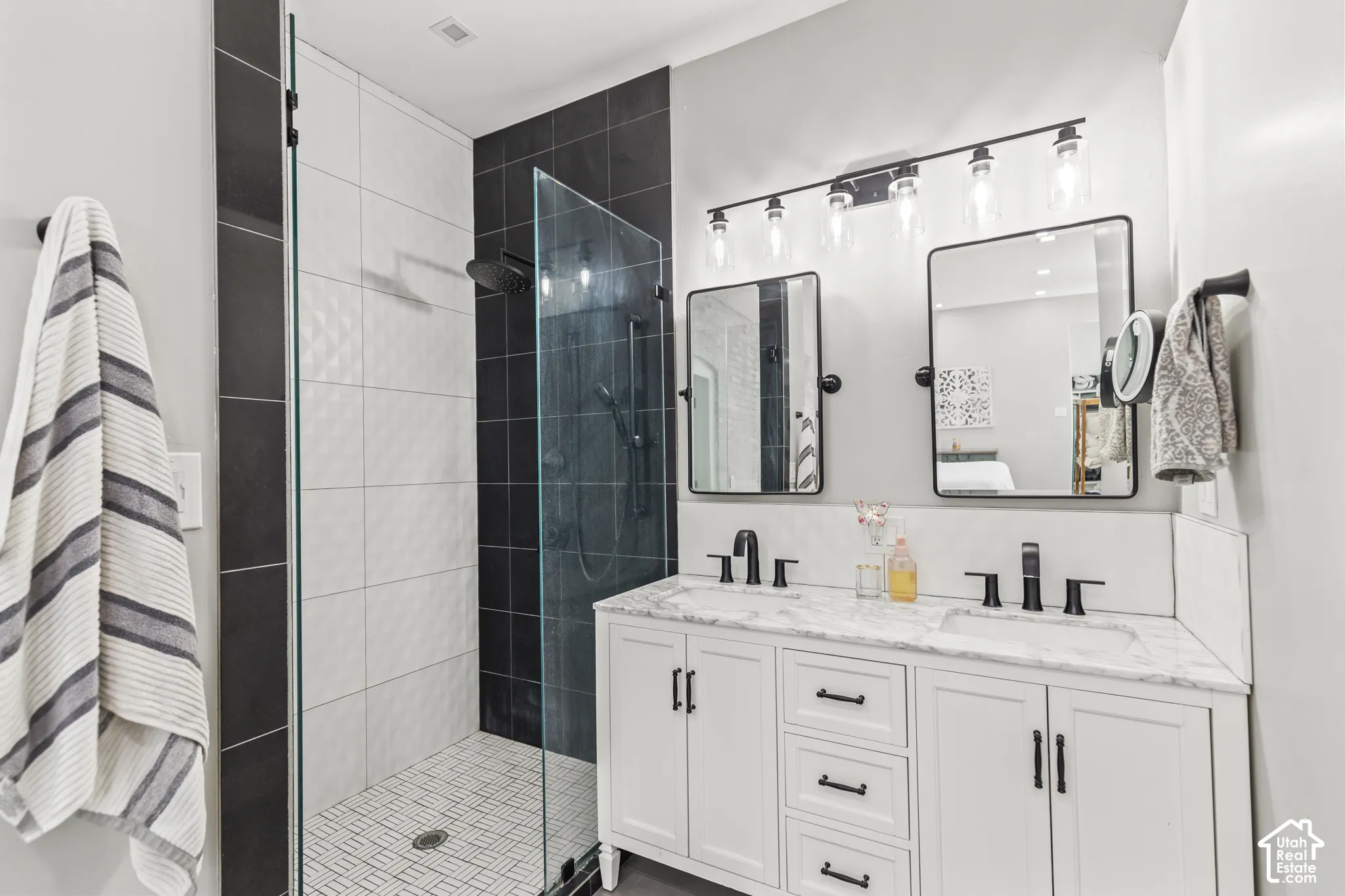 Walk-in shower with clear glass enclosure and black-tiled accent wall