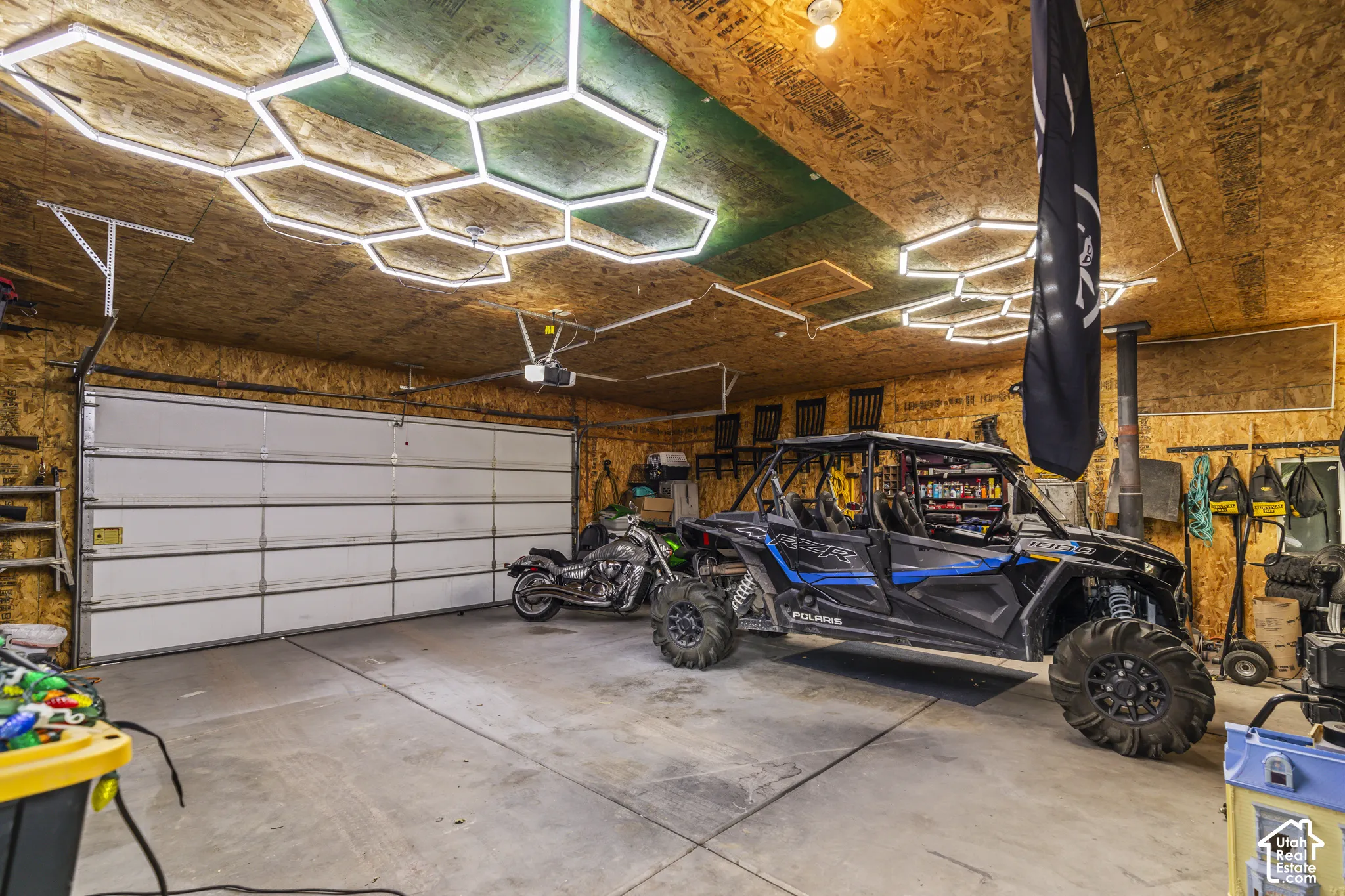 Attached garage with a large overhead door, concrete flooring, and unique hexagonal ceiling lighting