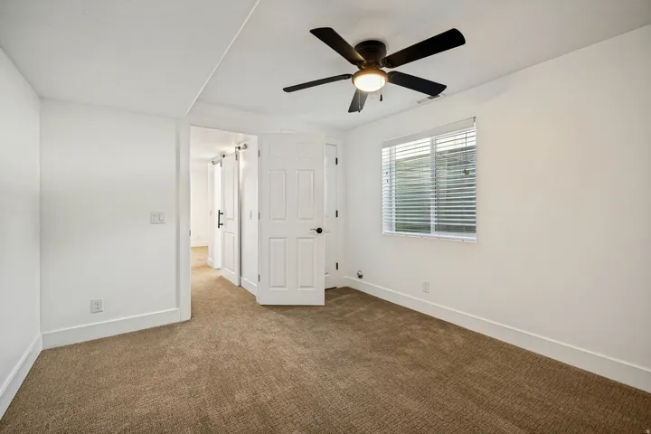 Plush carpeting, a ceiling fan with integrated lighting, window with blinds, and white interior doors