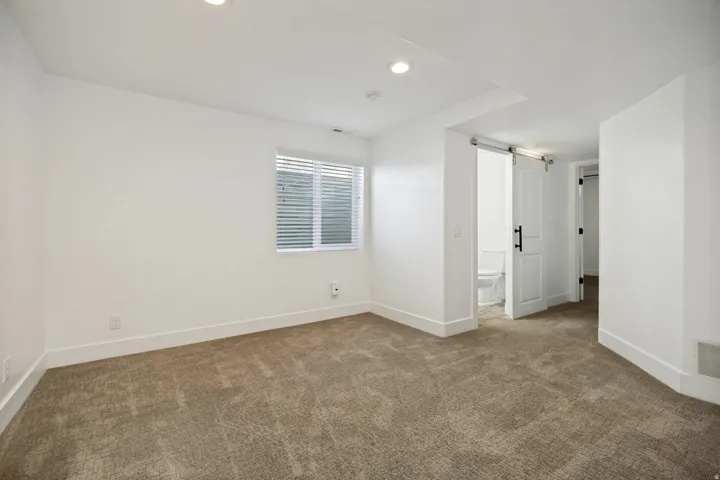 Recessed lighting illuminates neutral carpeting and white walls