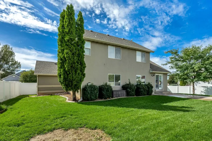 Expansive backyard featuring a manicured lawn, established landscaping, and a patio area