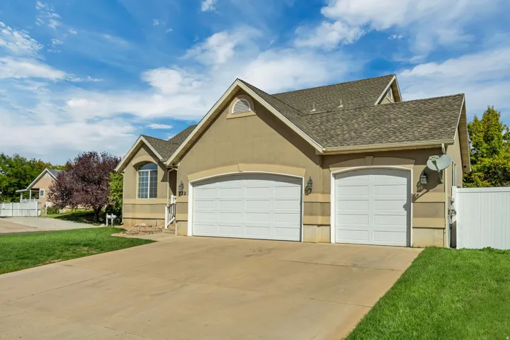 Stucco exterior with stone accenting, an arched window, and a two-car garage